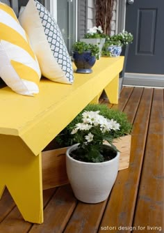 a yellow bench sitting on top of a wooden floor next to potted plants and flowers