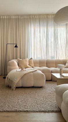 a living room filled with furniture and a large window covered in white drapes