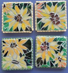 four pieces of art glass with yellow and green flowers in them on a blue surface