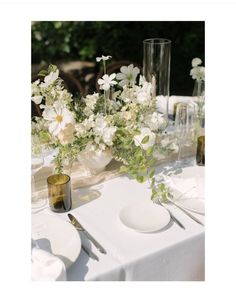 the table is set with white flowers and silverware