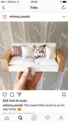 someone is holding up a fake couch made out of wood and white fabric with pillows on it