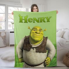 a woman holding up a green and white blanket with the words henry printed on it