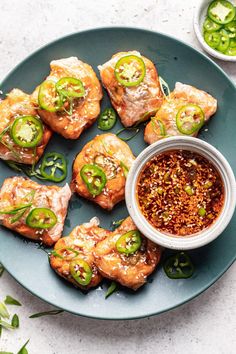 a blue plate topped with meat covered in sauce next to green peppers and jalapenos