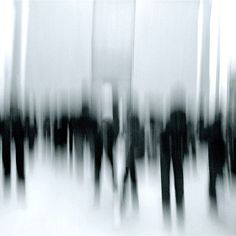 black and white photograph of people walking in the rain with tall buildings behind them on a foggy day