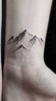 a woman's foot with a mountain tattoo on it