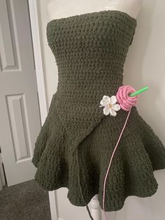 a crocheted dress is displayed on a mannequin with a flower in the center