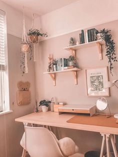 a desk with some books and plants on it in front of a wall mounted shelf