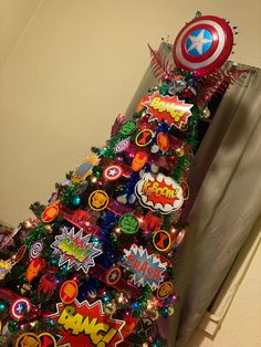 a decorated christmas tree with captain america stickers on it's top and decorations around the base