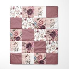 a pink and white patchwork quilt with flowers on the front, hanging on a wall