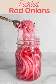 a jar filled with red liquid sitting on top of a white marble counter next to a spoon