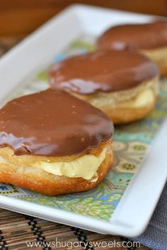 two chocolate covered donuts sitting on top of a white plate