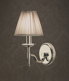 a lamp that is on the wall next to a light fixture with a white shade