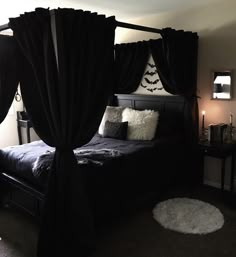 a bed with black drapes and pillows on top of it next to a night stand