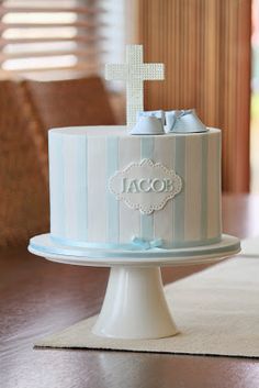 a blue and white striped cake with a cross on top is sitting on a table