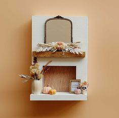 a shelf that has some flowers on top of it and a mirror above the shelf