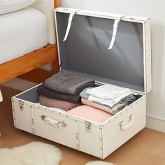 an open suitcase sitting on the floor next to a bed with white sheets and blankets