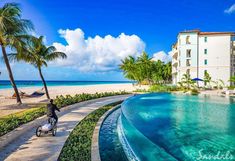 a person riding a scooter on the beach in front of a building and palm trees