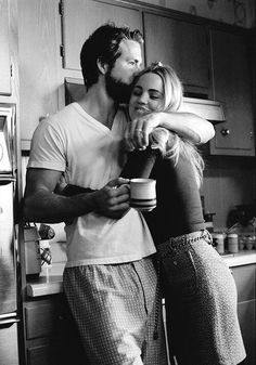 black and white photograph of a man hugging a woman while she holds a coffee cup