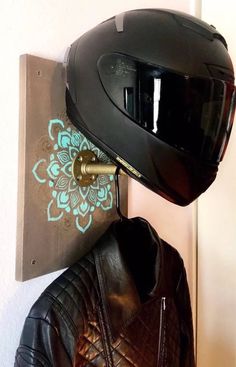 a motorcycle helmet mounted to the wall next to a leather jacket hanging on a hook