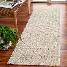 a white rug on top of a wooden floor next to a chair and potted plant