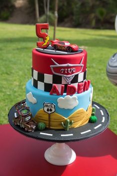 a birthday cake with cars on it sitting on top of a table