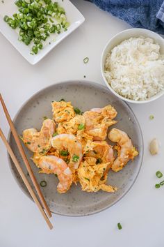 shrimp and rice on a plate with chopsticks next to the bowl full of rice