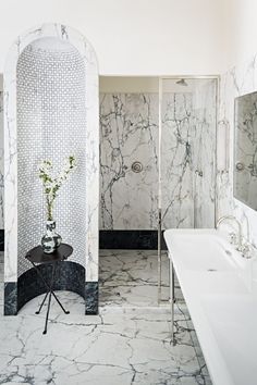 a bathroom with marble walls and flooring next to a bathtub, shower stall and sink