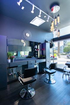 a salon with chairs, mirrors and lights on the ceiling in front of a large window