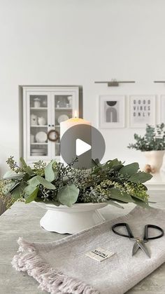 a table topped with a white bowl filled with plants