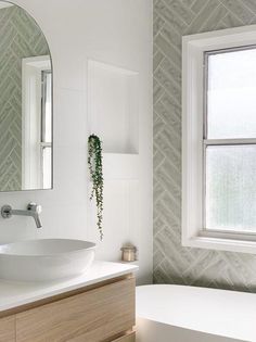 a white sink sitting under a bathroom mirror next to a bath tub and counter top