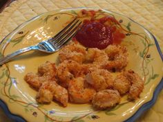 a yellow plate topped with tater tots covered in ketchup next to a fork