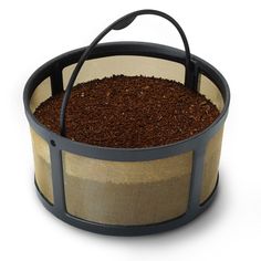 a basket filled with coffee beans on top of a white table next to a black handle