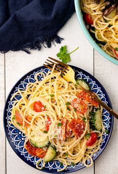 a plate of pasta with tomatoes, zucchini and parmesan cheese