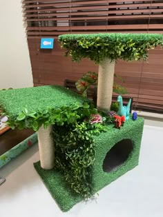 a cat house made out of artificial grass and fake plants in the shape of trees