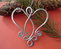 a metal heart decoration sitting on top of a table next to pine cones and needles