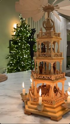 a christmas tree with lit candles in front of it and a building model on the table