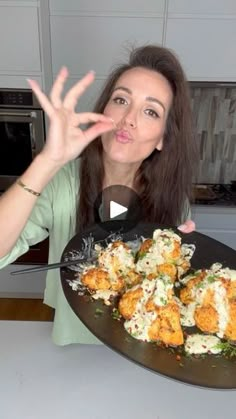 a woman is making a funny face while holding a platter with food on it