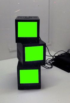 two black boxes with green squares on them sitting in front of a laptop and other electronic equipment