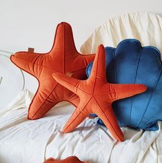 two starfish pillows sitting on top of a bed next to an orange and blue pillow