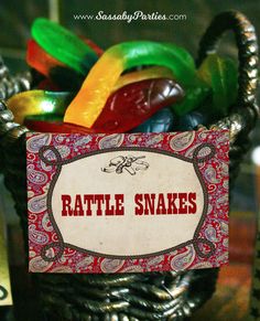 a small basket filled with lots of colorful gummy bears next to a sign that says rattle snakes