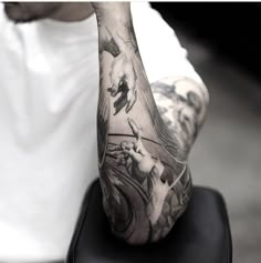 a man sitting on top of a chair with his arm covered in tattoos