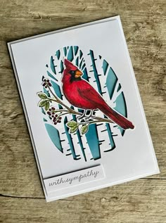 a red bird sitting on top of a wooden table next to a paper cutout