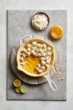 a table topped with a pie covered in toppings next to orange juice and lime slices