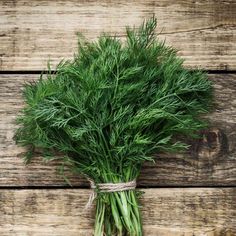 a bunch of green herbs tied to a wooden table