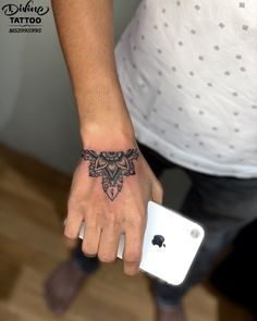 a person's hand with a tattoo on the wrist and an apple phone in front of them