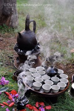 the tea set is sitting on the ground next to flowers