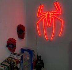 a spiderman neon sign hanging from the side of a wall next to a bookshelf