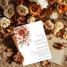 a wedding card with flowers on it sitting next to some dried leaves and other flowers