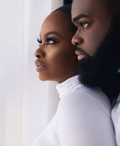 a man and woman standing next to each other in front of a white wall wearing black makeup