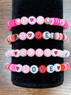 three bracelets with love written on them and hearts in pink, white, and red